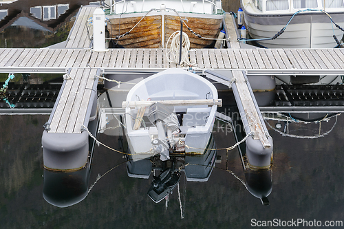 Image of A top-down view of a single motorboat tied to a serene, empty dock, surrounded by still waters.