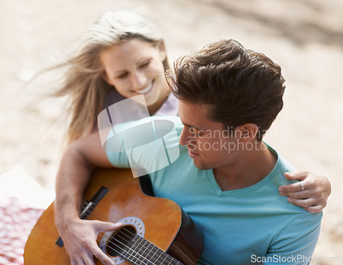 Image of Couple, picnic and playing guitar for romance, love or song in outdoor bonding, fun or relaxing together in nature. Man and woman smile with instrument for acoustic sound, strumming or music outside