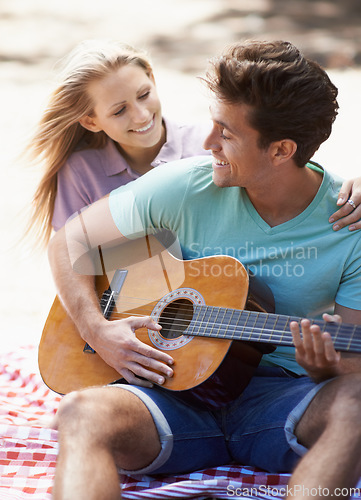 Image of Happy couple, picnic and playing guitar for romance, love or music in outdoor bonding, fun or relaxing together in nature. Man and woman smile with instrument for acoustic sound or songs outside