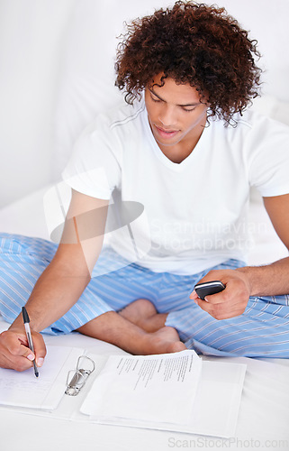 Image of Working, man in bedroom and cellphone for work from home, writing and sitting in pyjamas for freelance. Technology, entrepreneur and remote worker for online job, documents and business projects