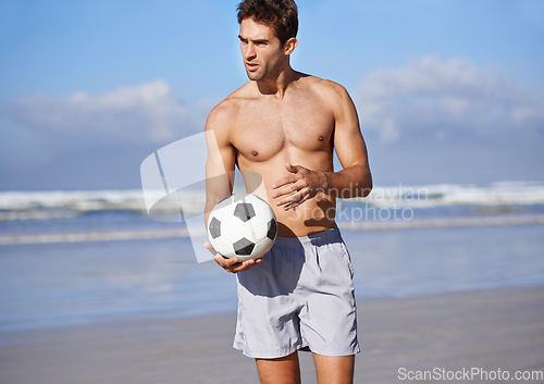 Image of Man, beach and soccer ball for game, sports or exercise in outdoor hobby for training or practice. Young male person or football player on ocean coast for match or cardio workout by the seaside