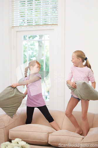Image of Happy kids, pillow fight and girls playing on sofa in living room together for fun bonding at home. Couch, siblings or children enjoying playful game, entertainment or weekend with cushions in lounge