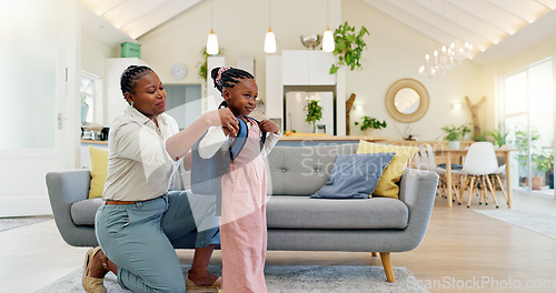 Image of Talking, happy and a mother with a child getting ready for school in the morning. Kiss, laughing and an African mom helping a little girl with a bag in the living room of a house for kindergarten