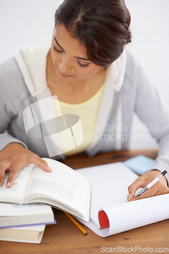 Image of Reading, woman writing and student studying in college, learning and work on school project at desk. Books, serious person at table and education, knowledge and info for test on notepad in university