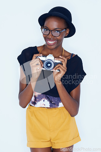 Image of Black woman, photographer and positive in studio with camera, creativity and media for artist with creative talent. Young person, happiness and face for photoshoot, lens and focus by white background