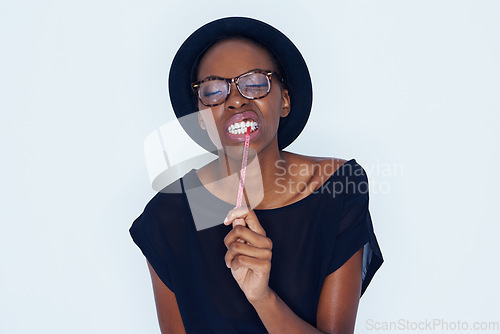 Image of Face, fashion and black woman eating candy in studio on white background for sugar craving. Food, glasses and biting sweets with young african model eyes closed for appetite, greed or hunger