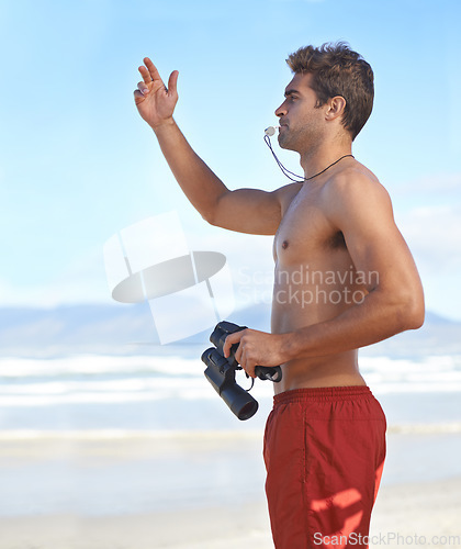 Image of Man, binoculars and lifeguard on beach with whistle in security, emergency or health and safety. Young male person monitoring, bay watch or patrol by the ocean coast or sea in surveillance or danger