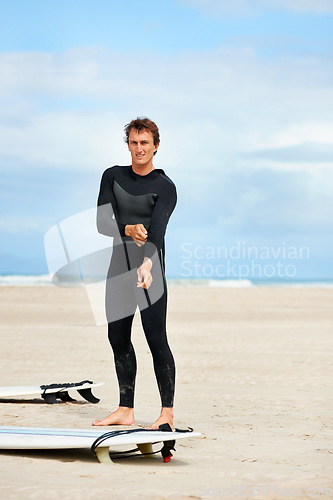 Image of Surfer, man and portrait with surfboard on beach with wetsuit, blue sky or dressing with mock up space. Extreme sports, athlete and person by ocean for training, surfing workout or holiday adventure