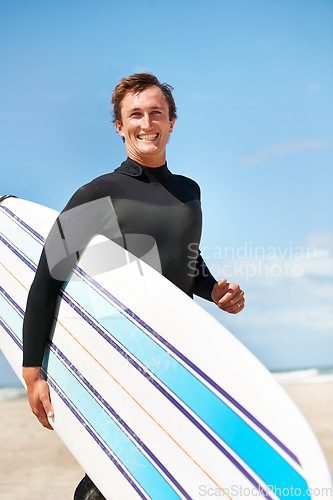 Image of Beach, smile and man with surfboard for exercise, fitness workout or body health in summer outdoor. Surfer, wetsuit and happy person by ocean for water sports, travel or holiday vacation in Hawaii