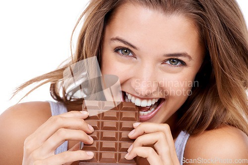 Image of Woman, eating chocolate and portrait, candy and sweet tooth with pleasure and craving sugar on studio background. Hungry, snack and meal for comfort, dessert and sweets for calories, diet and bite