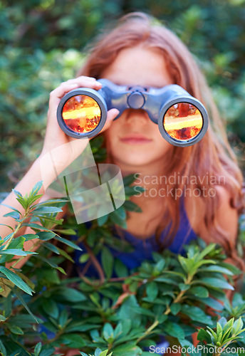 Image of Girl, kid with binoculars and search in nature for learning and fun, forest and adventure at summer camp. Young camper, leaves and explore environment outdoor in bush with hiking and discovery