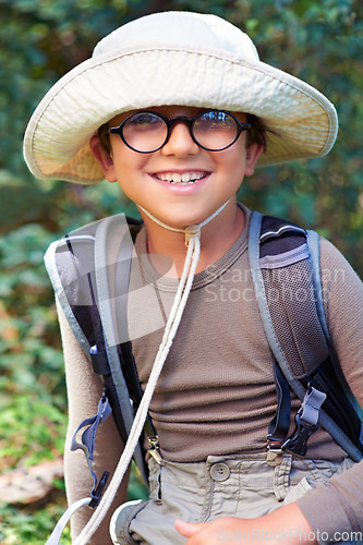 Image of Boy, kid and hiking in nature, portrait with glasses and scout outdoor for adventure, travel and fun with backpack. Discover, exploring and summer camp with happy camper in park, youth and recreation