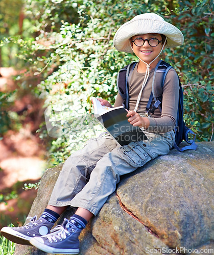 Image of Boy, kid and hiking, relax on rock and book for reading, backpacking and adventure outdoor. Student on school field trip, nature and forest for discovery and exploration, smile in portrait and travel