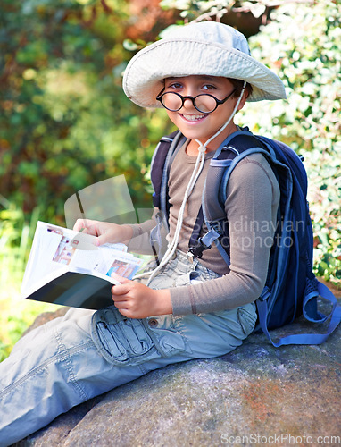 Image of Boy, kid and hiking, book for reading and relax on rock, backpacking and adventure outdoor. Student on school field trip, nature and forest for discovery and exploration, smile in portrait and travel