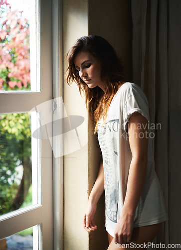 Image of Thinking, depression and serious woman by window in home, lonely or mental health anxiety. Dream, stress and sad young person with worry for mistake, frustrated in crisis or remember memory of trauma
