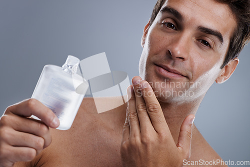 Image of Studio, portrait and man with cologne for skincare, grooming and facial treatment or aftershave. Model, face and happy with bottle for cosmetics product, fragrance and male beauty by gray background