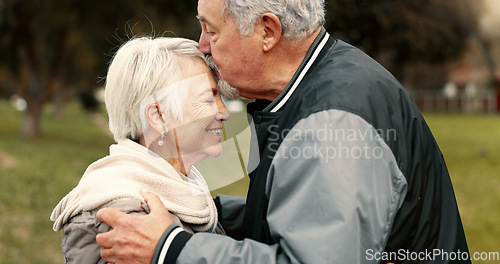 Image of Love, smile and kiss with a senior couple hugging outdoor in a park together for a romantic date during retirement. Happy, support and an elderly man and woman bonding in a garden for romance