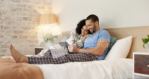 Image of Couple, tablet and relax in home bedroom, laugh or morning with video, movie or meme for love, care or hug. Man, woman and digital touchscreen for typing, social network app or bond together in house