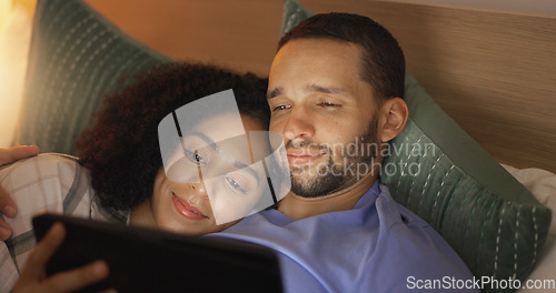 Image of Couple, smile and relax in bedroom with tablet at night, streaming movie or film. Happy, technology and man and woman in bed on social media, browsing online app and watching video together in home