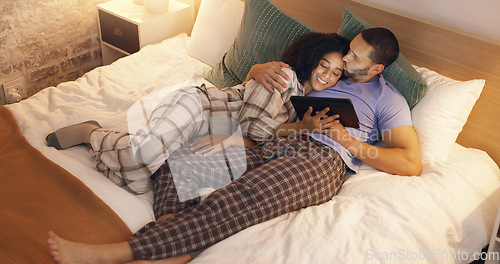 Image of Couple, happy and hug in bedroom with tablet at night, streaming movie and relax. Smile, technology and man and woman in bed on social media app, watching online video and bonding together in home.