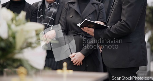 Image of Bible, hands and family at funeral, cemetery or burial ceremony religion by coffin tomb. Holy book, death and grief of people at graveyard, Christian priest reading spiritual gospel and faith in God