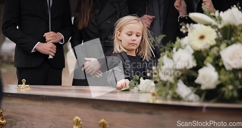 Image of Death, grief and girl at funeral with flower on coffin, family and sad child at service in graveyard for respect. Roses, loss and people at wood casket in cemetery with kid crying at grave for burial