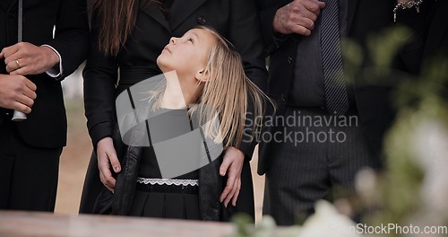 Image of Mourning, grief and family with girl at funeral, flowers on coffin, death and sad child at service in graveyard. Support, loss and people at casket in cemetery with kid crying at grave for burial.