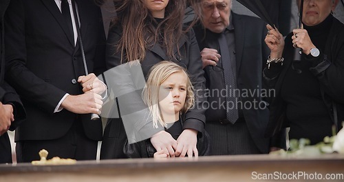 Image of Loss, grief and people at funeral with umbrella, flowers and coffin, family with sad child at service in graveyard. Roses, death and group in rain at casket in cemetery with kid at grave for burial.