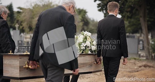 Image of Coffin, men and pallbearers walking at graveyard ceremony outdoor at burial tomb. Death, grief and group casket at cemetery, carrying to funeral and family service of people mourning at windy event