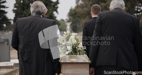 Image of Men, coffin and pallbearers walking at cemetery ceremony outdoor at burial tomb. Death, grief and group casket at funeral, carry to graveyard and family service of people mourning at windy event.