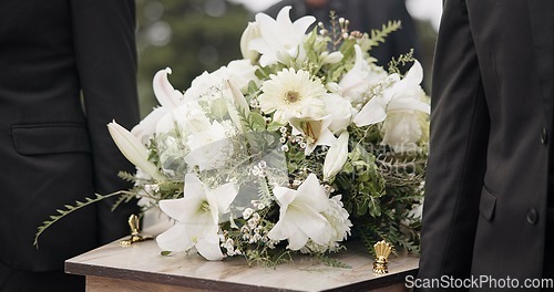 Image of Carrying coffin, flowers and people at funeral for service, mourning and at the graveyard. Closeup, support and group of family or friends with respect while holding casket during a ceremony together