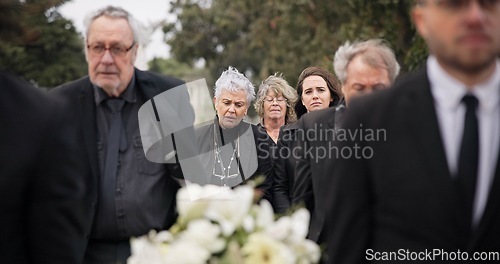 Image of Pallbearers, men and walking with coffin in funeral, ceremony or mourning event at graveyard with sad, grief and flowers. People, support and walk with family in memorial service together with casket