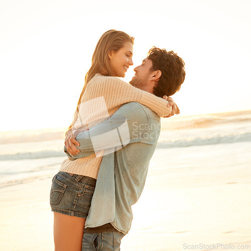 Image of Smile, hug and young couple at beach on vacation, adventure or holiday for valentines day. Sunset, love and man carry, embrace and bond with woman by ocean for weekend trip on romantic date.