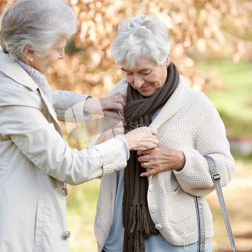 Image of Senior friends, care and support by outdoor in nature, together and bonding on retirement on holiday. Elderly women, help and tie button on vacation in countryside, love and happy in park in winter