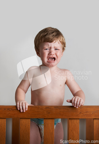 Image of Sad toddler, crying and portrait of baby in his crib or home with emotional anger or loss in childhood. Problem, trouble and house with a frustrated young male kid, infant or boy with tears or noise