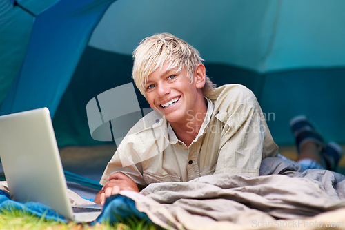 Image of Child, boy and happy with laptop in tent for camping, social media and online movie with portrait in nature. Person, face and kid with smile outdoor on grass for gaming, vacation and holiday fun