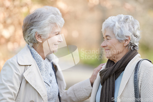 Image of Senior women, care and touch in park by autumn leaves, together and conversation on retirement in outdoor. Elderly friends, smile or communication on vacation in england, bonding or social in nature