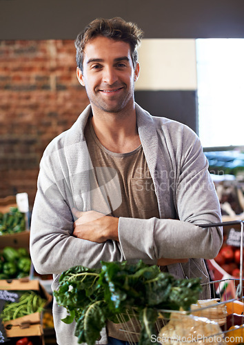 Image of Portrait, basket or happy man shopping in supermarket for grocery promotions, sale or discounts deal. Arms crossed, smile or customer buying groceries for healthy food, organic vegetables or spinach