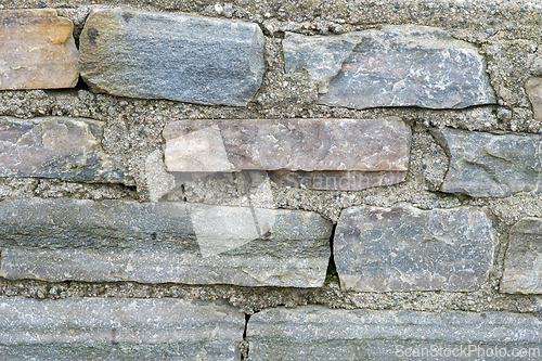 Image of A detailed look at the varied texture and colors of aged stones in a wall, captured in daylight.