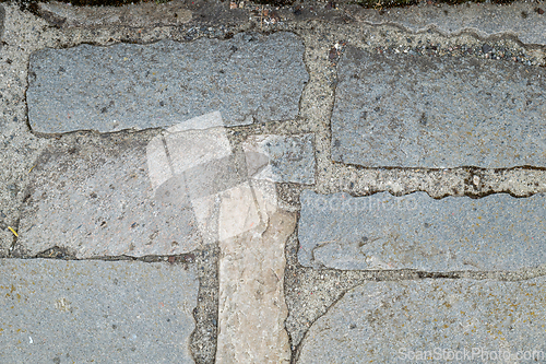 Image of A detail of worn and uneven stone slabs forming an old pathway.