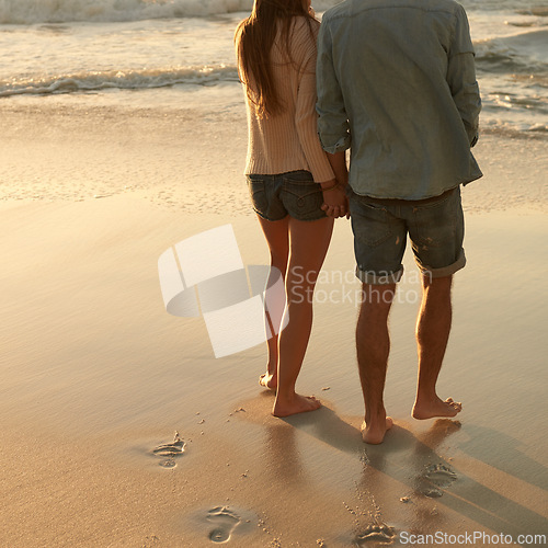 Image of Beach, sunset and couple holding hands with love, support and relationship security on summer holiday in Portugal. Mockup space, sand and back of partner, soulmate or people on evening walk together