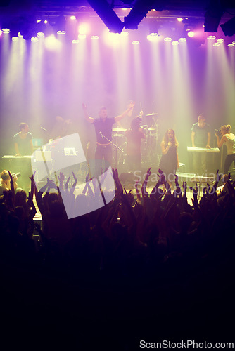 Image of Concert, audience and stage with hands from fans at dj, band and festival event with lights and music. Rock show, dance and party with excited crowd with rave, techno and entertainment at venue