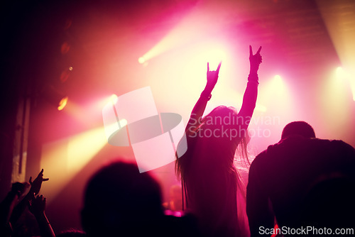 Image of Rock, concert and people dance at night, event or party at music festival with fans in audience at stage. Crowd, energy and woman with hands in sign for metal, sound or social celebration at rave