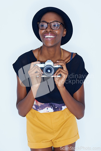 Image of Black woman, photographer and happiness in studio with camera, creativity and talent in media in artist career. Young person, positive and vision for photoshoot and focus lens by white background
