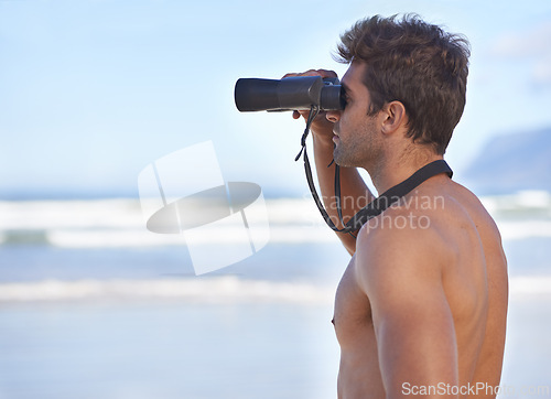 Image of Man, binoculars and lifeguard on beach in search or checking danger for health and safety. Face of male person in fitness for security, bay watch or patrol by the ocean coast or sea in surveillance