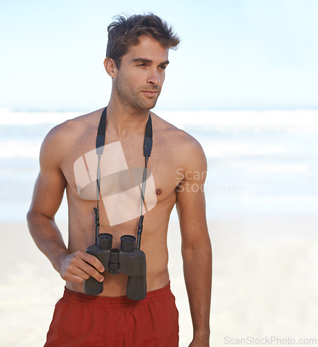 Image of Man, binoculars and lifeguard on beach for security, emergency or health and safety. Face of young male person in fitness for monitoring, bay watch or patrol by the ocean coast or sea in surveillance