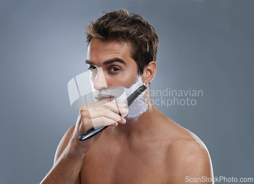 Image of Man, shaving cream and studio portrait with blade for wellness, skincare and grooming by grey background. Person, model and self care with beard, facial hair removal and product for cosmetic change
