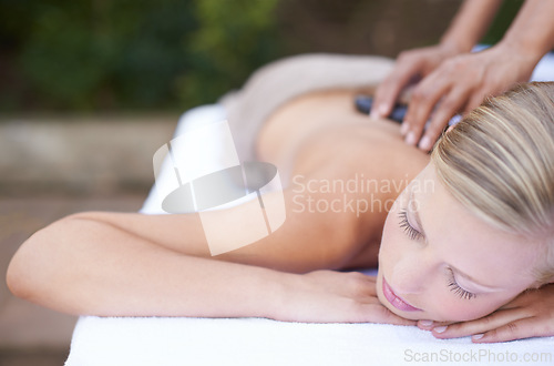 Image of Woman, massage and hot stones to relax, back and spa for treatment and stress relief therapy. Sleeping, masseuse and wellness in resort, peaceful and hands for luxury bodycare and tranquility