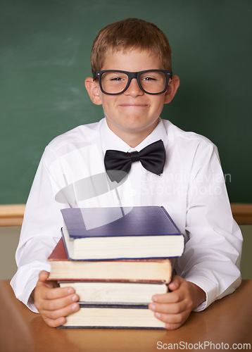 Image of Boy child, happy and portrait with books, classroom and learning for exam, assessment and studying for knowledge. Student kid, notebook and smile for education, development and glasses at table