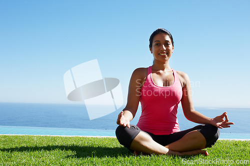 Image of Grass, yoga and portrait of woman in lotus pose by water for holistic balance, mindfulness and exercise. Meditating, hands in prayer and person by ocean for wellness, health and zen energy outdoors